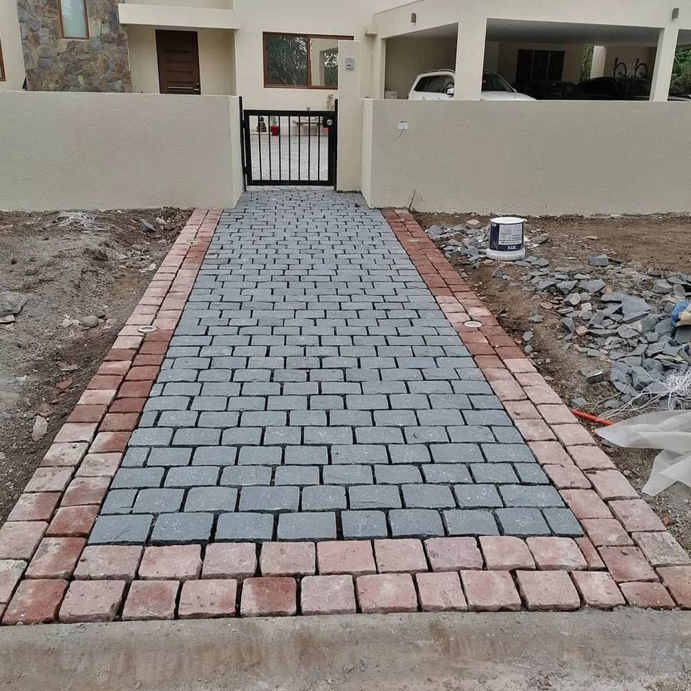 Acceso de adoquines grises con borde de ladrillo