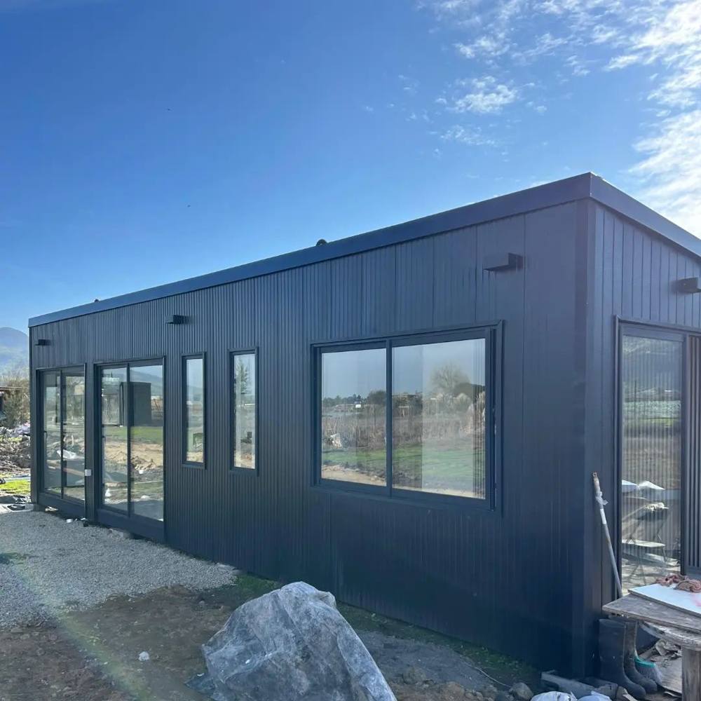 Casa modular de revestimiento negro con ventanales