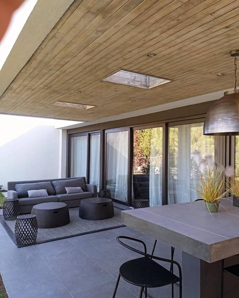 Living exterior bajo cubierta de madera con ventanales