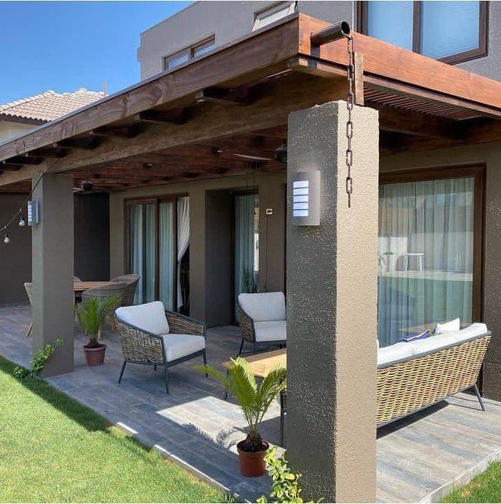 Terraza techada con estructura de madera y comedor exterior